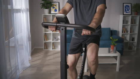 adult-man-is-using-stationary-bike-in-home-middle-aged-person-is-caring-about-health-keeping-fit-at-self-isolation-time